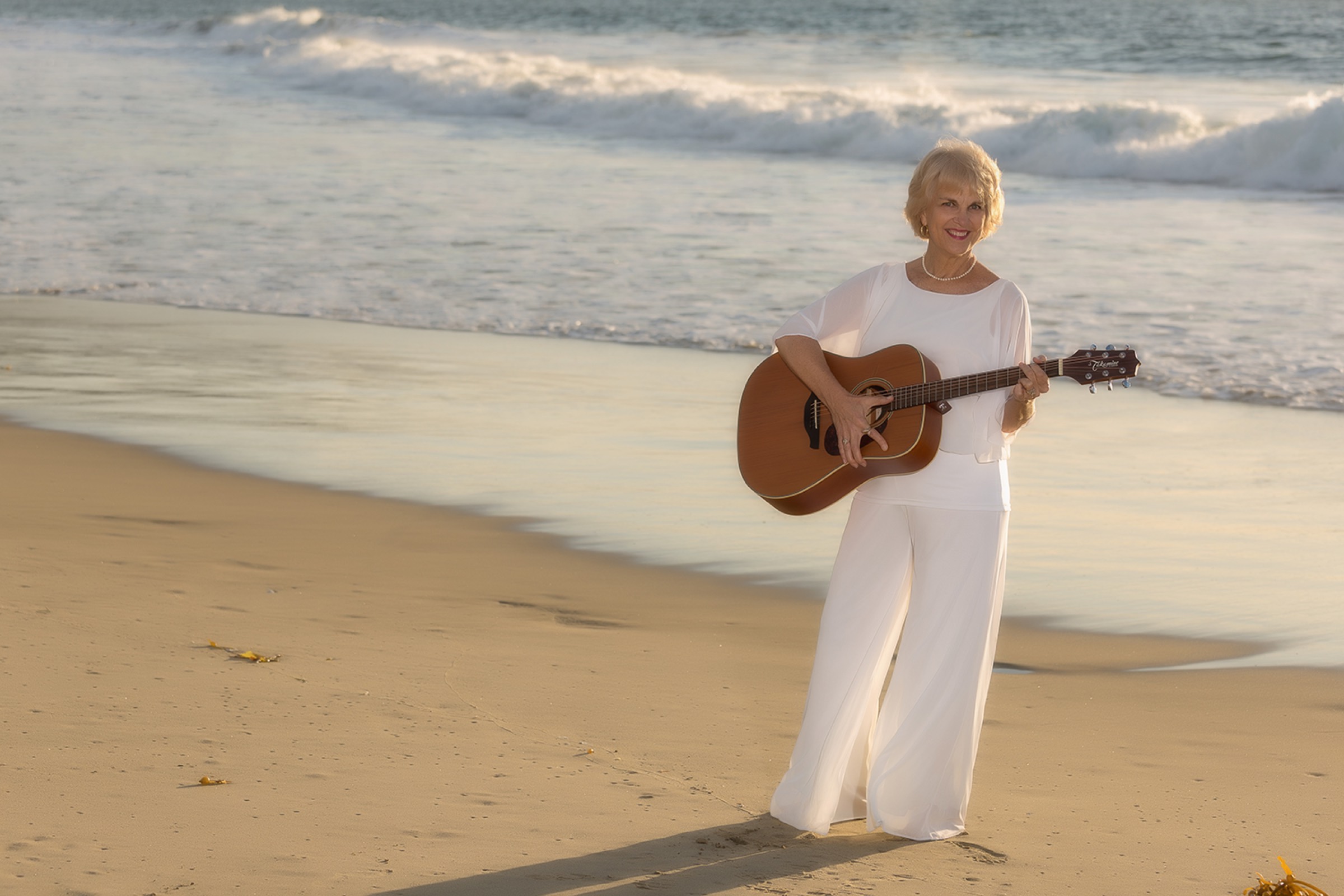 Cynthia Jordan with guitar on the Sarasota shore